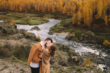 A happy couple in love in casual clothes travel together, hike and have fun in the autumn forest, enjoy nature on a weekend in fall. A man and a woman on a romantic date countryside