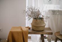 Dry Flowers In Straw Basket On Wooden Bench In Living Room