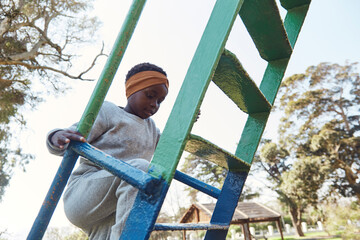 Young black girl climbing ladder for slide.