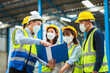 © SEVENNINE_79 - The factory employee consists of engineers, foreman, technicians, and related department staff. Wear a mask, hard hat, and vest. meeting before starting work inside the warehouse. Teamwork concept.