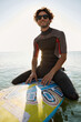 © Drobot Dean - Young surfer sitting on surfboard in sea water