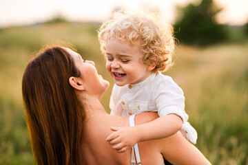 Playful mother and son while walking in a summer field