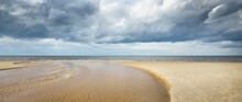 Crystal Clear Water And Sandy Shore Of The Baltic Sea On A Sunny Spring Day. Shallow Water. Dramatic Cloudscape. Latvia