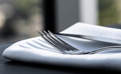 Wall Mural - Fork and knife with white napkin on table in luxury restaurant outdoors, fine dining menu for wedding or event and food catering service concept.