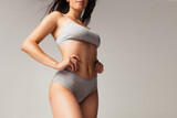 Beautiful body of young caucasian woman in grey lingerie isolated on gray studio background. Natural beauty concept. Bottom view