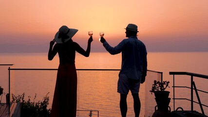 Wall Mural - A couple on summer holidays enjoys the summer sunset view over the mediterranean sea with a glass of wine