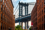 Fototapeta Panele - Manhattan Bridge between Manhattan and Brooklyn over East River seen from a narrow alley enclosed by two brick buildings on a sunny day in Washington street in Dumbo, Brooklyn, NYC
