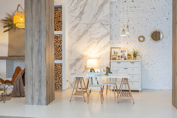 Fashionable modern interior of a light studio apartment with wooden columns in the loft style, decorated with brick, marble and wood with stylish furniture and white walls