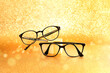 A pair of  black eyeglasses on golden glitter background