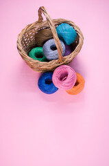 Poster - Vertical shot of colored cotton threads in a basket on a pink background