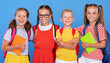 © JenkoAtaman - Happy children, girls and boys, standing with backpacks behind and exercise books, smiling at camera