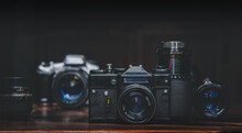 Close-up Of Vintage Cameras And Lenses On Table Against Black Background