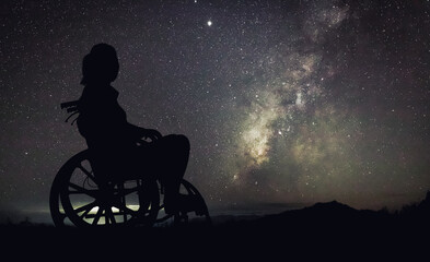 Wall Mural - silhouette disabled handicapped woman is sitting on wheelchair looking night landscape with colorful