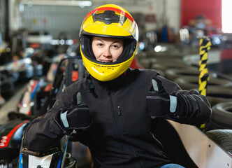 Jolly woman in helmet standing near sport cars for karting in sport club