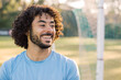 © Austockphoto - Close up photo of a smiling man with curly hair with beard wearing blue shirt on a sunny day