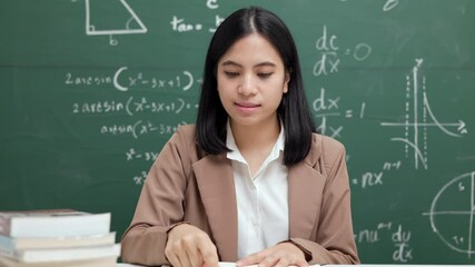 Wall Mural - Young asian teacher woman sitting using laptop video conference with student. Female teacher training the mathematics in classroom from live stream with computer online course.