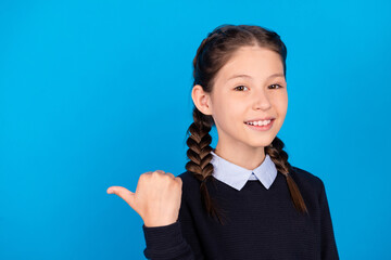 Sticker - Photo of good mood smiling schoolgirl point thumb copyspace advertise product isolated on blue color background