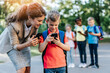 © hedgehog94 - First day at school. Mother leads her son in first grade and showing him something on mobile phone.