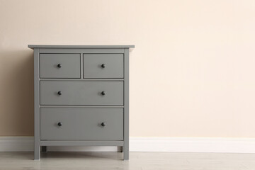 Poster - grey chest of drawers near beige wall. space for text