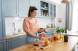 © Syda Productions - culinary, drinks and people concept - happy smiling young woman making orange cocktail at home kitchen