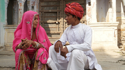 Closeup of an Indian couple in traditional outfits sitting on the stone stairs outdoors.