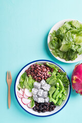 Healthy vegan salad vegetables with lettuce, corn salad, radish, kidney bean, azuki bean and green bean in a bowl on color background