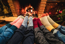Legs View Of Happy Family Wearing Warm Socks In Front Of Fireplace During Christmas Day - Focus On Left Socks
