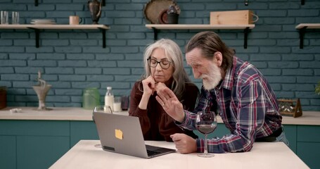 Wall Mural - Cheerful senior couple watching news on laptop