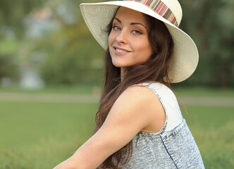 Wall Mural - Beautiful smiling woman in hat looking outdoors summer.green trees background. Closeup