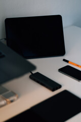 Poster - Vertical shot of a turned-off black smartphone, laptop, keyboard, tablet, and pen on a table