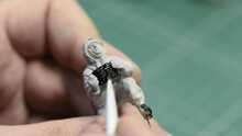 Scale Modeling 1:35. A Man Painting Plastic WWII Soldier Figure In Winter Uniform. Figure Of A German Soldier Glued From Parts.