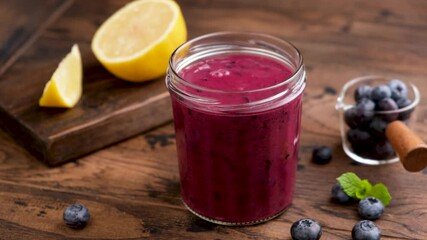 Wall Mural - Blueberry smoothie pouring in a glass jar. Thick purple blueberry acai smoothie, rich in vitamins and antioxidants. Superfood drink