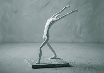 Plaster sculpture of sportsman in winner pose on concrete background