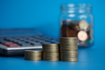 stacks of money coin with calculator and book bank, Business and financial investment concept on blue background