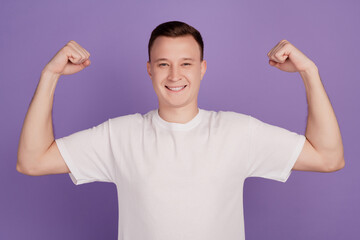 Wall Mural - Portrait of cool strong guy raise hands show muscle on violet background