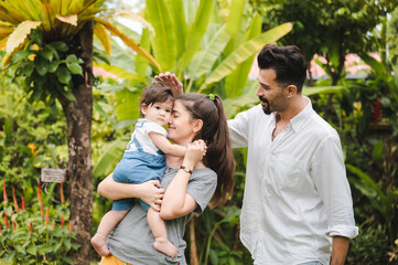 Wall Mural - happy family at home together concept, children joying with father and mother on summer nature garden outdoors, people having fun, boy or girl and young woman are smiling lifestyle outside the park