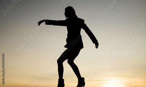 female silhouette on sunset sky background of dancing woman, silhouette