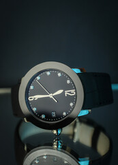 Poster - Closeup shot of a hand watch with a bstrap on a reflective surface