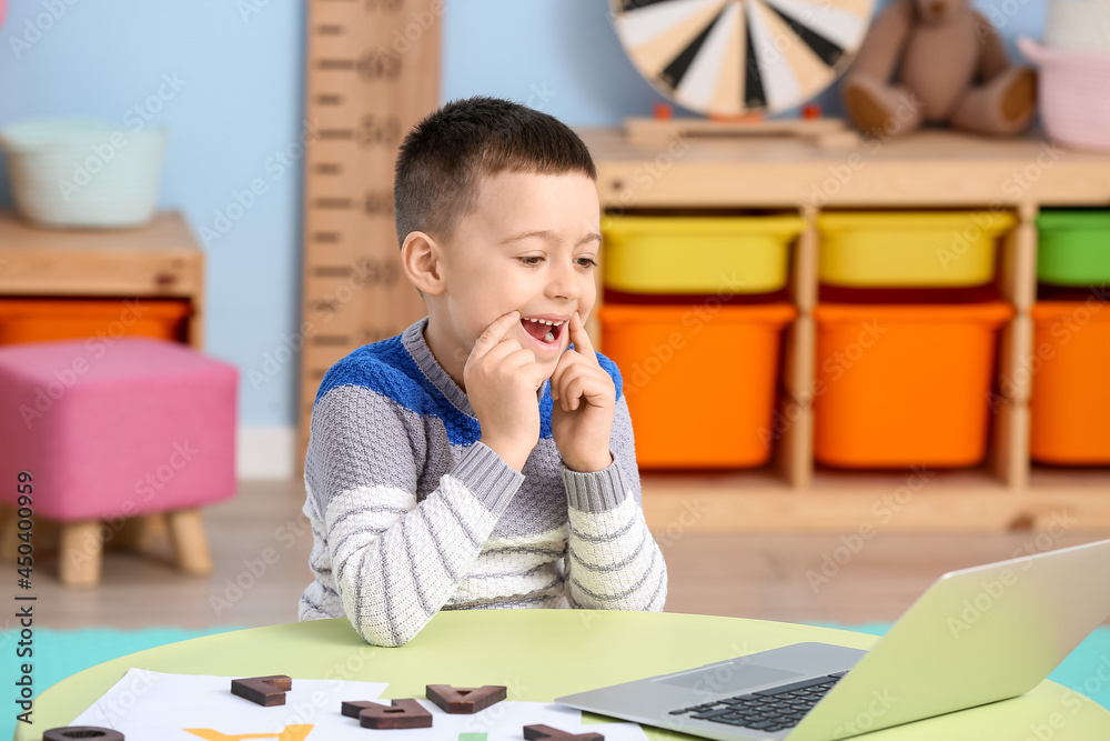 Little boy with laptop training pronounce letters at home