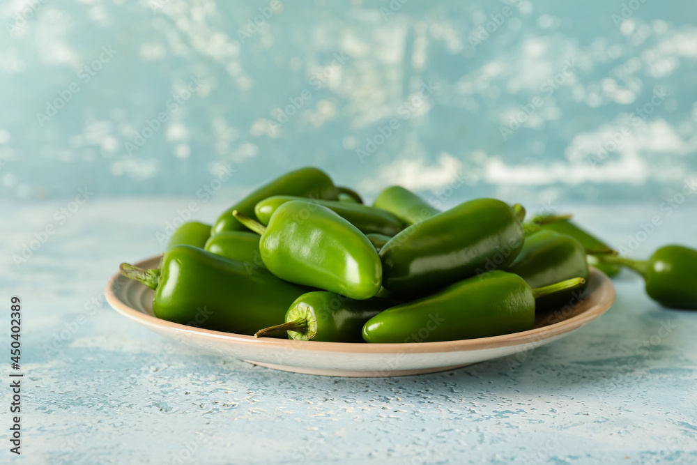 Plate with green jalapeno peppers on color background, closeup