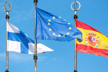 Close-up view of European Union flag waving against blue sky hanging by finnish and spanish flags. Global business and communications. International relations theme.