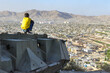 Boy sitting on Destroyed Tank on the hills over Kabul City in Afghanistan