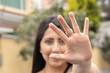 © Alejandro - face of attractive young woman with her long black hair showing the palm of her hand grasping a stop sign to the camera, lifestyle