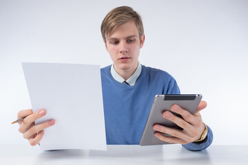 Poster - Online training. A young man with a sheet of paper and a tablet computer in his hands. Search for information on the Internet. Using gadgets at work and at school. Training on online courses. 
