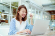 © Ekkasit A Siam - A beautiful woman wearing an Asian white shirt is sitting in front of a laptop computer shopping online with a happy smile in a bakery shop.