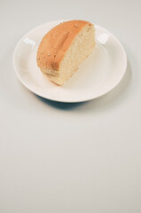 Sticker - Vertical shot of half bread bun on a plate isolated on white background