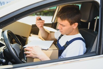 Young Delivery Man Checking List On Clipboard In car