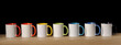 7 white mugs of rainbow colors on a dark background