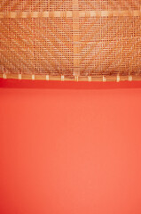 Wall Mural - Vertical shot of bamboo wicker tray isolated on red background