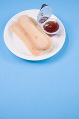 Sticker - Vertical shot of ladyfinger cookies on a plate with ketchup dip isolated on blue background